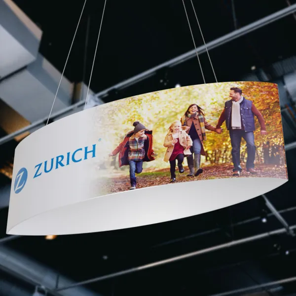 A curved banner displaying a happy family walking through a fall landscape, hangs indoors with the Zurich logo visible.