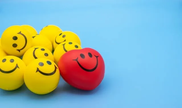 a selection of yellow and red smiley stress balls against a blue background for how to use a stress ball