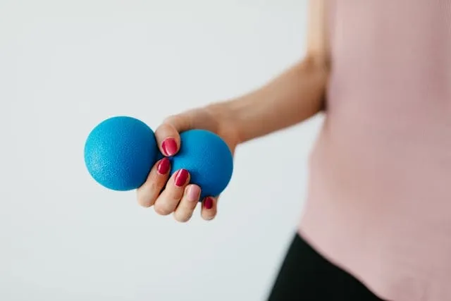 a person holding a blue stress ball against a white background for how to use a stress ball