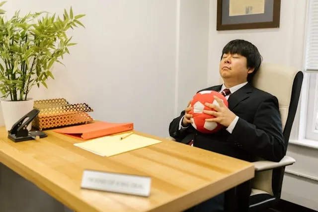 a person in an office chair squeezing a ball with eyes closed for what are stress balls made of