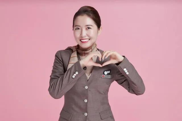 a flight attendant in front of a pink background for why do flight attendants wear scarves