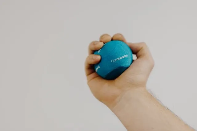 a person squeezing a blue stress ball for how to inflate exercise ball